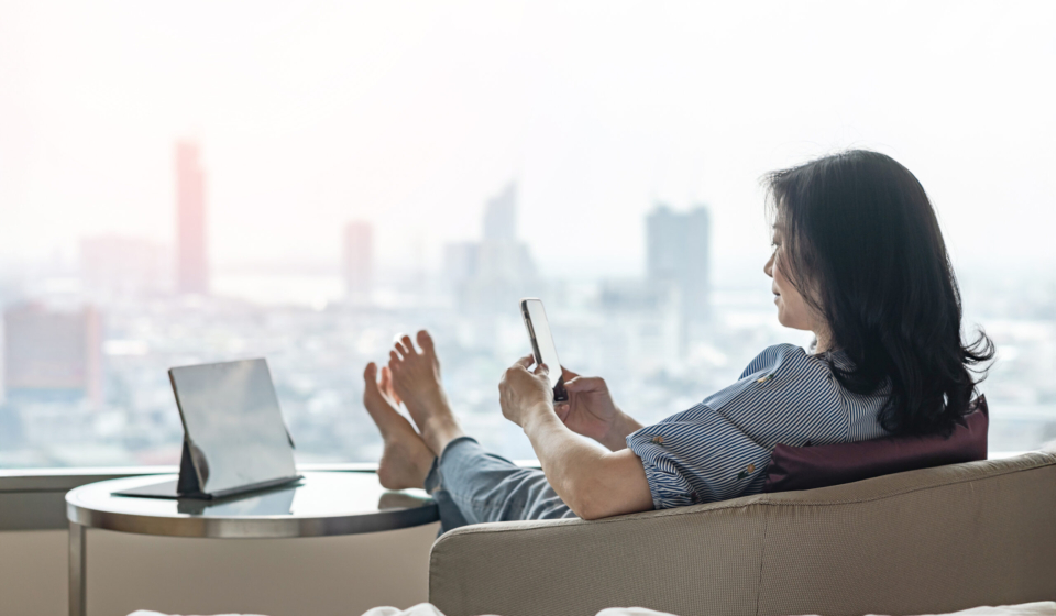 Work-Life balance, life quality, work and travel concept with business woman relaxing sitting in rest, take it easy in modern city hotel guest room or luxury home living room with notebook and smartphone