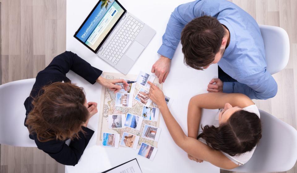 Female Travel Agent Giving Information To A Young Couple For Vacation Package